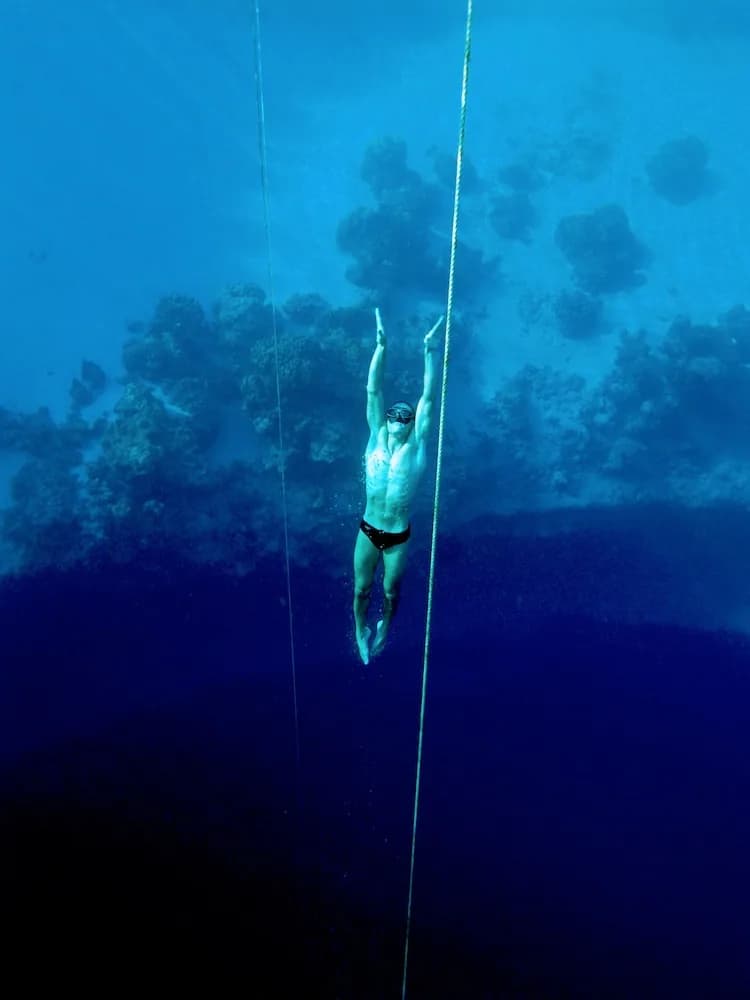 Freediver returning from depth assisted by a buddy