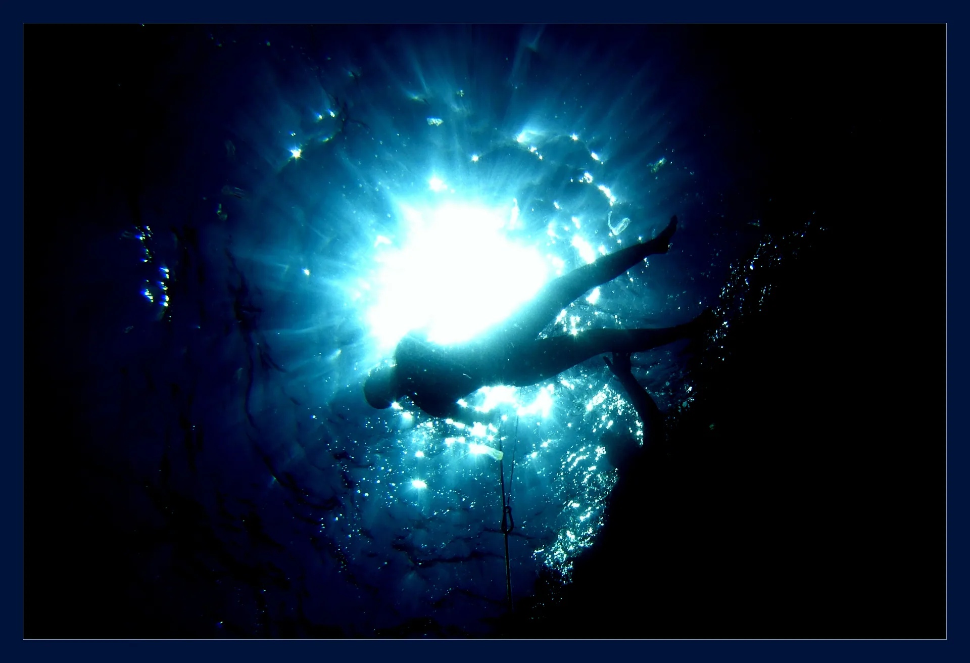 Freediver descending into the light of the surface ocean